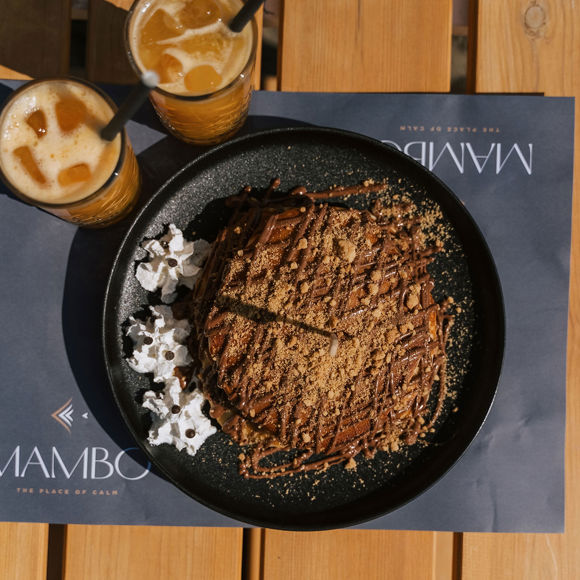 Close up of chocolate pancakes with crumbled biscuit topping and fresh orange juice