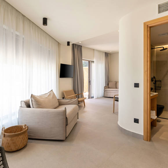 Cozy bright living area with a wall mounted TV and an open door revealing a comfortable bathroom