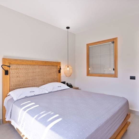 Maisonette suite bedroom with woven headboard, pendant lights and access to a modern bathroom