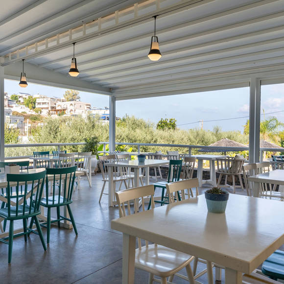 Covered outdoor dining area with colorful chairs, and surrounding greenery