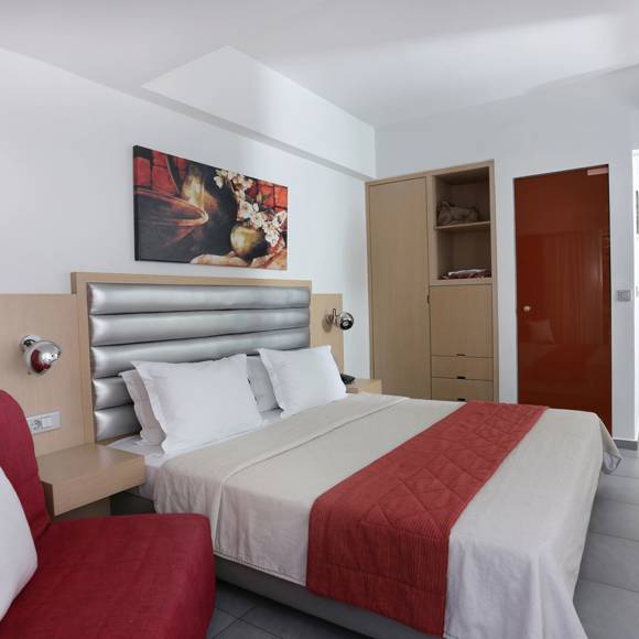 modern room with a double bed, red accents, built-in wardrobe, and minimal decor in warm tones