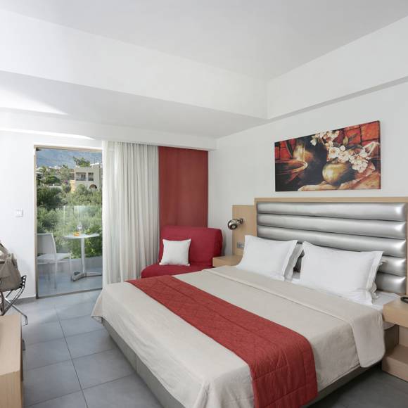 bright modern room with a double bed, a red armchair, balcony access, and minimalistic decor in warm tones