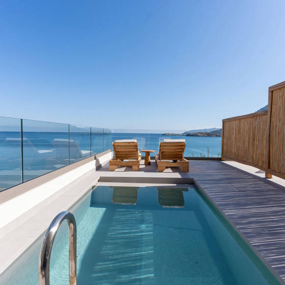 Private outdoor pool with sun loungers and sea view surrounded by glass and bamboo fencing