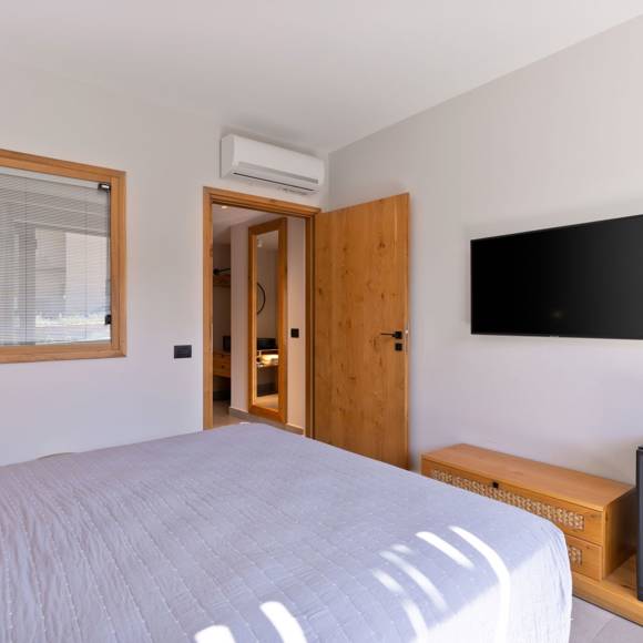 Bright bedroom in maisonette suite with wall-mounted TV, wooden accents and modern amenitites