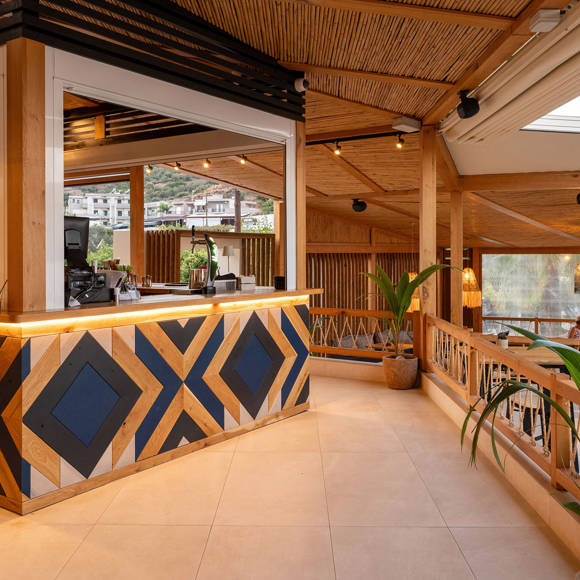Reception area of Mambo Beach restaurant with wooden decor, geometric counter and warm lighting