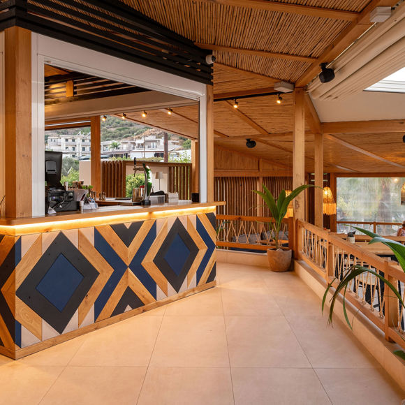 Reception area of Mambo Beach restaurant with wooden decor, geometric counter and warm lighting