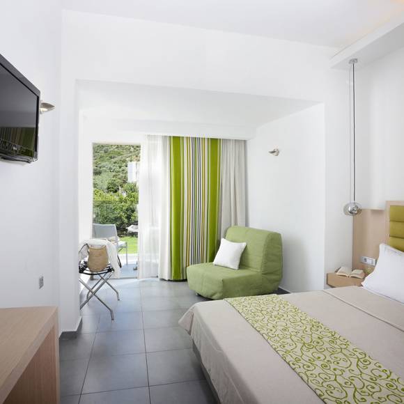 modern room with a double bed, a green armchair, a wall-mounted TV, balcony view and minimalistic decor