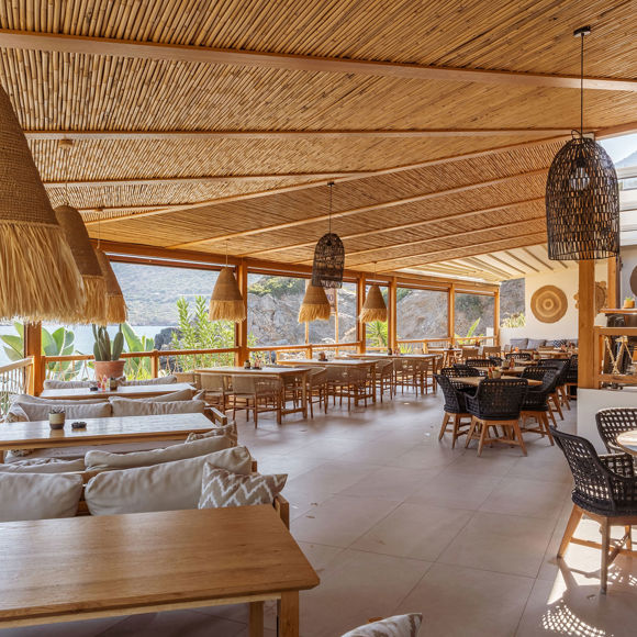 Spacious seafront lounge area at Mambo Beach Restaurant with wooden decor, woven pendant lights and cozy seating