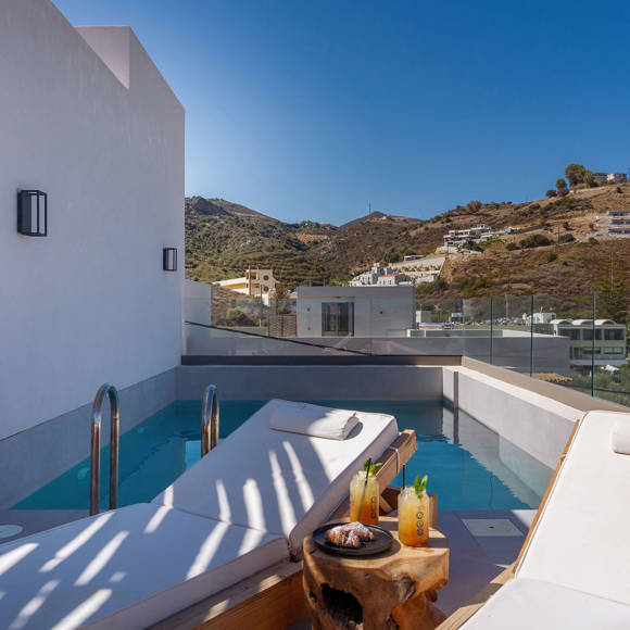 Junior suite outdoor terrace private pool area with a pair f wooden sun loungers and a table with drinks and pastries