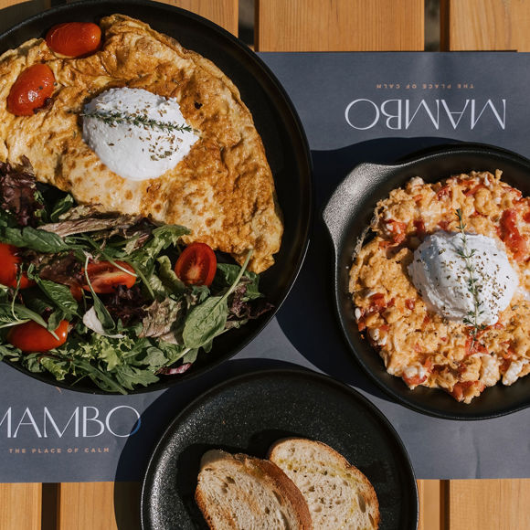 Close-up of brunch dishes with omelette, scrambled eggs, salad, and bread at Mambo Beach Restaurant