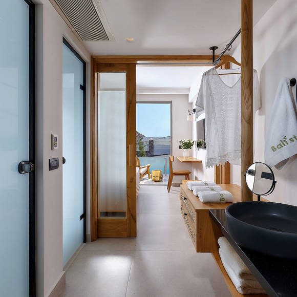 One bedroom suite bathroom area with a black sink, round mirrors, hanging area and access to the bedroom with a private balcony with view