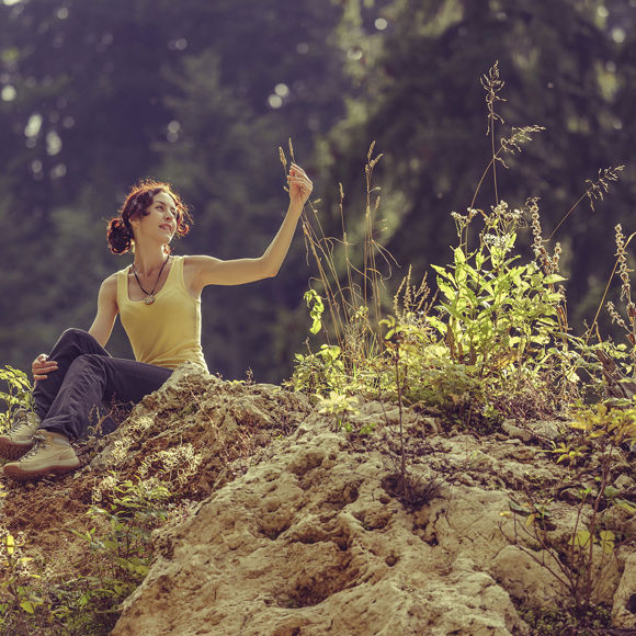 A woman sitting on a rocky outcrop, relaxing and enjoying the natural surroundings in Crete