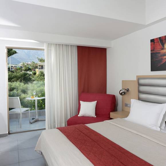 modern room with a double bed, a red armchair, balcony view and minimalistic decor in warm tones