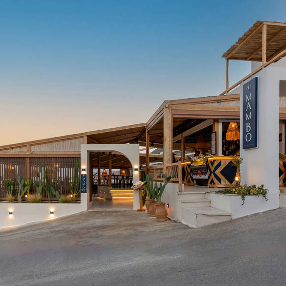 Evening exterior view of Mambo Beach Restaurant with wooden pergolas and sea facing ambience