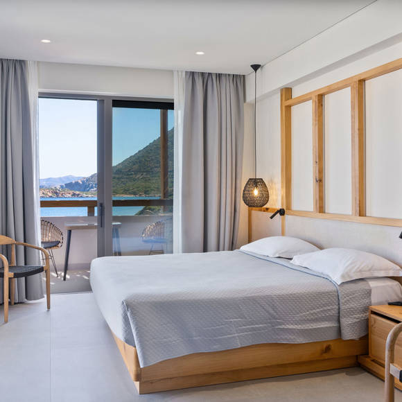 Junior suite with a double bed, wooden accents, pendant lights and a balcony with direct sea view