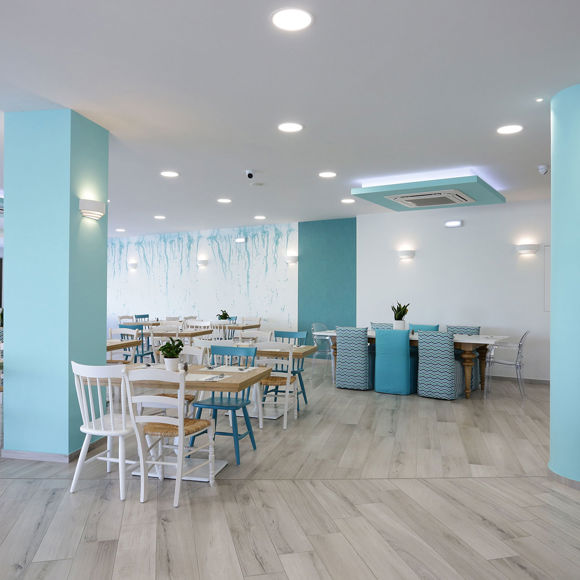 Bright and modern main restaurant with pastel blue decor, wooden tables and natural light