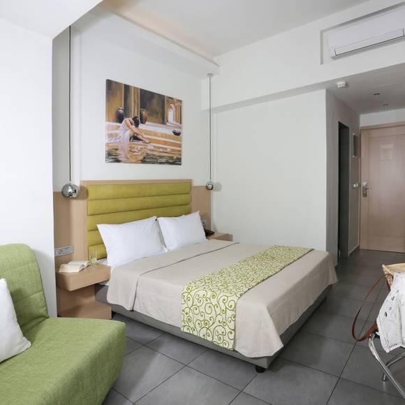 Modern room with a double bed, a green armchair, wall-mounted TV and minimalistic decor in natural tones