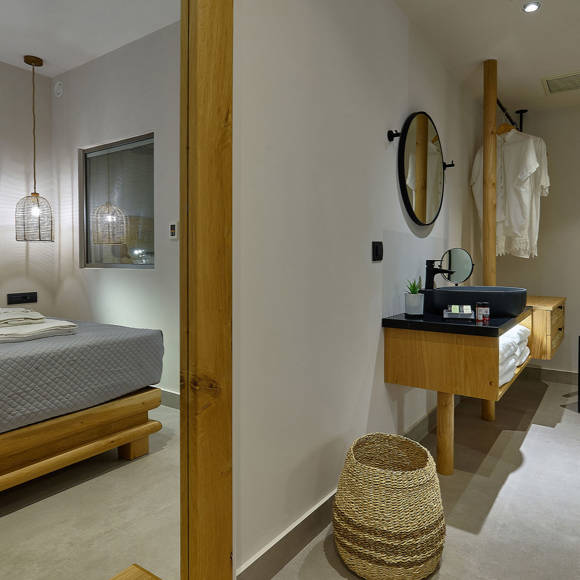 Junior suite with a double bed and open bathroom area with a clothes hanger, vanity and a chair