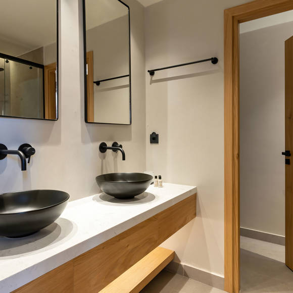 Bathroom featuring double black vessel sinks, wall-mounted faucets and a wooden door