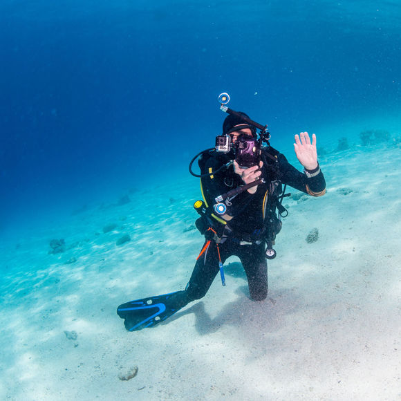Scuba diver greeting the camera underwater