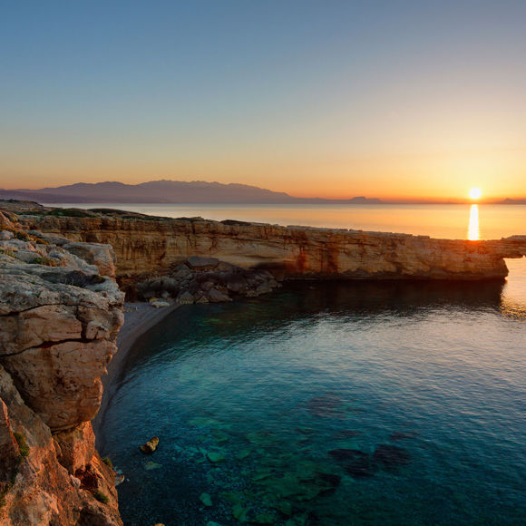 Sunset view of the Camarola arch in Bali, Crete with golden light reflecting on the sea