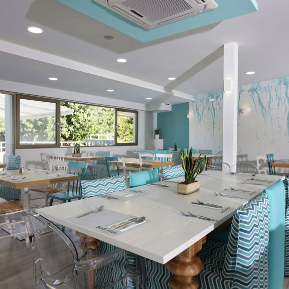 Main restaurant interior with set tables, pastel blue accents and large windows with garden view