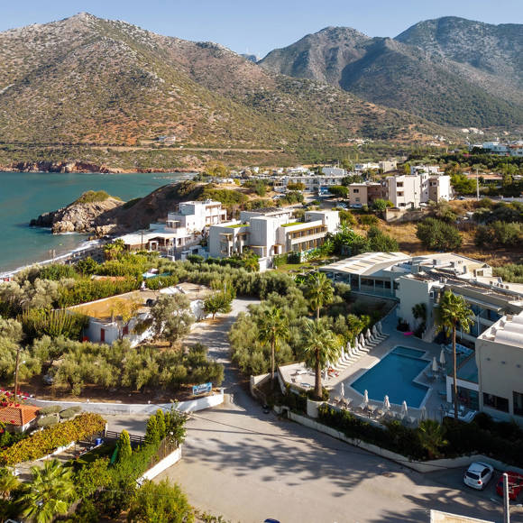 Aerial view of Bali Star Hotel surrounded by olive trees, mountains and coastline near the bay 