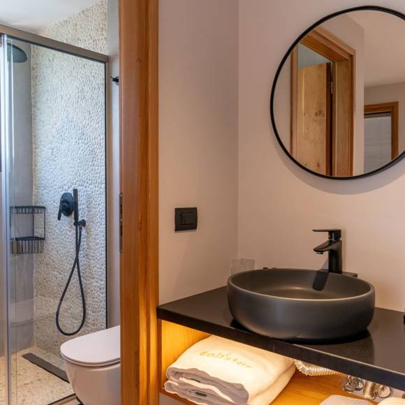 Maisonette suite bathroom with black sink, round mirror and walk in shower