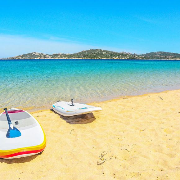 Two kayaks parked on the sandy beach where the sea meets the shore 