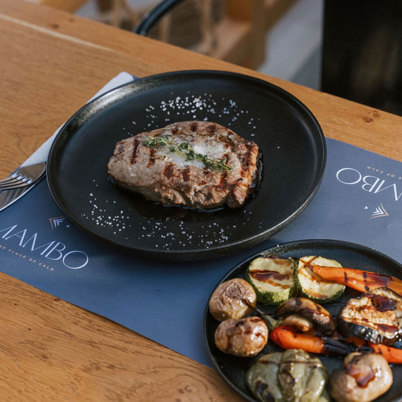 Grilled steak with sea salt and herbs, served with a side of roasted vegetables at Mambo Beach Restaurant