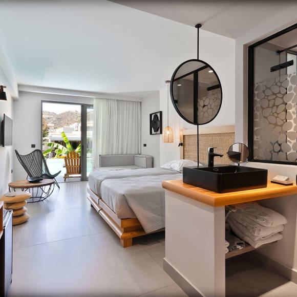 Modern junior suite with a double bed, open vanity area, glass shower, wooden furniture and access to a pool with garden view