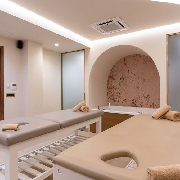Spa room featuring two massage beds, a built in tub and soft ambient lighting