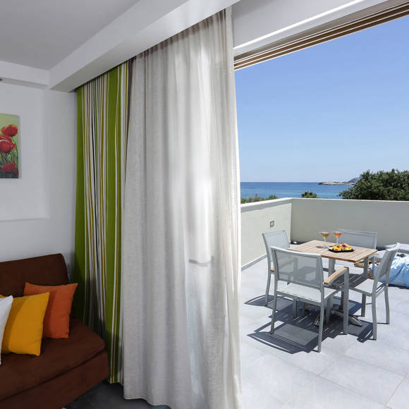 Living area with brown sofa and open terrace with dining table sun loungers and sea view