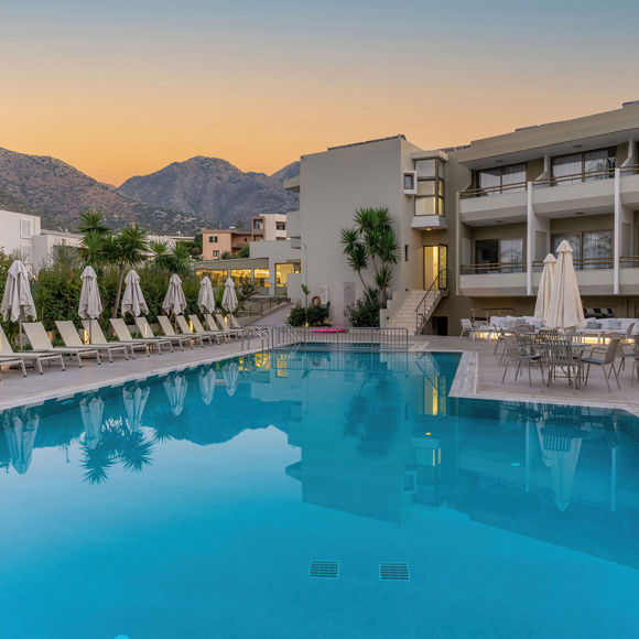 View of the pool with sunbeds lined up on the left and outdoor dining tables on the right