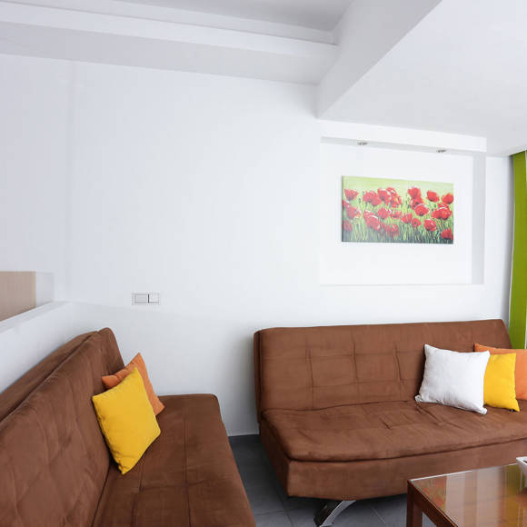 living area with two brown sofas, colorful cushions, a coffee table and green-striped curtains