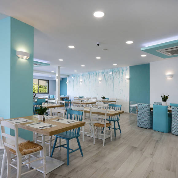 Interior of the main restaurant with pastel blue accents, wooden tables and natural daylight