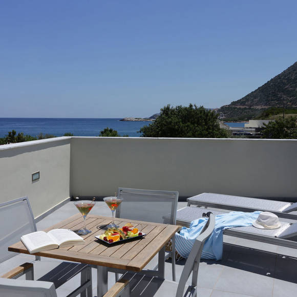 Terrace with dining table served with drinks and fruit , sun loungers, and a sea view
