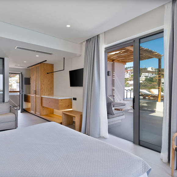 Junior suite with a double bed, sitting area, wooden furniture and access to terrace with private pool and a wooden pergola for shading