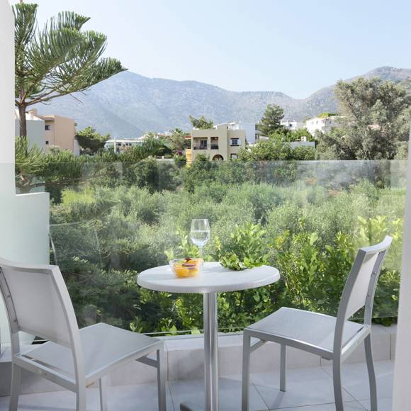 balcony with a pair of chairs and a table overlooking greenery 